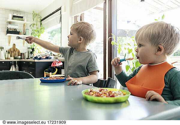 Siblings having meal on dining table at home