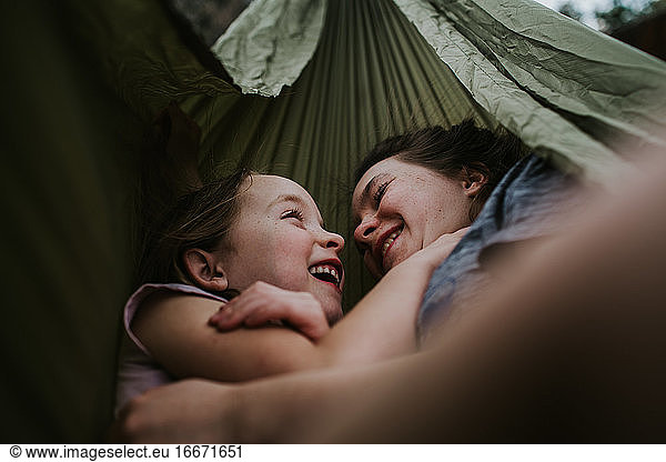 Siblings hugging and smiling in hammock outside