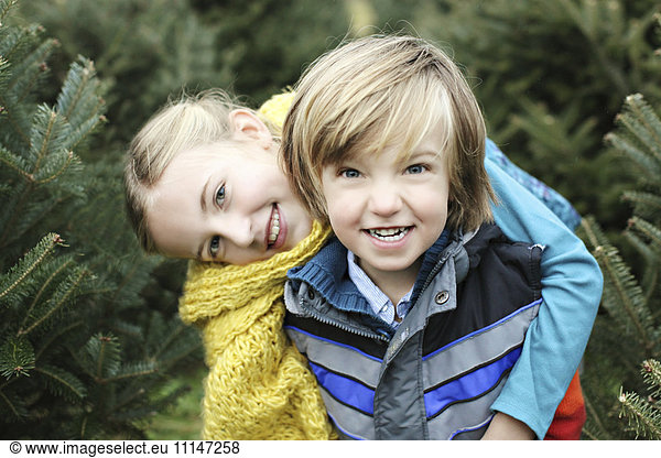 Siblings hugging near pine trees