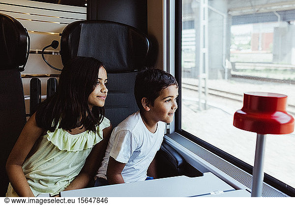 Siblings looking through train window while traveling together
