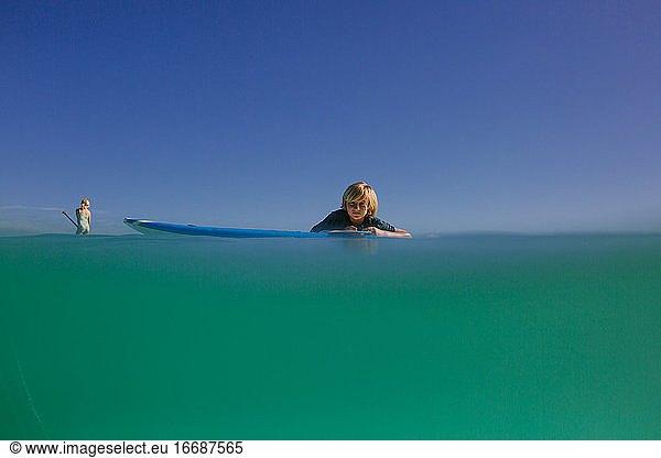 Siblings paddleboard in turquoise waters of Hawaii