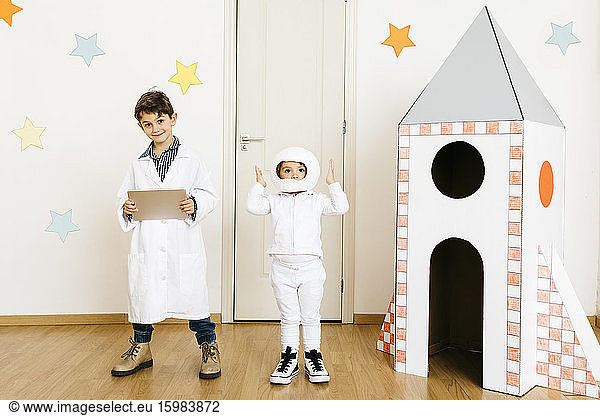 Siblings playing astronaut and researcher at rocket