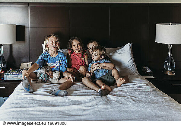Siblings sitting and laughing on hotel bed on vacation in Palm Springs