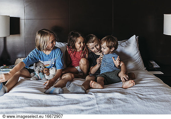 Siblings sitting and smiling on hotel bed on vacation in Palm Springs