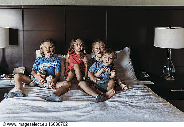 Siblings sitting and smiling on hotel bed on vacation in Palm Springs