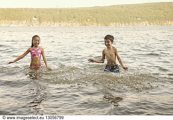 Siblings splashing water in lake