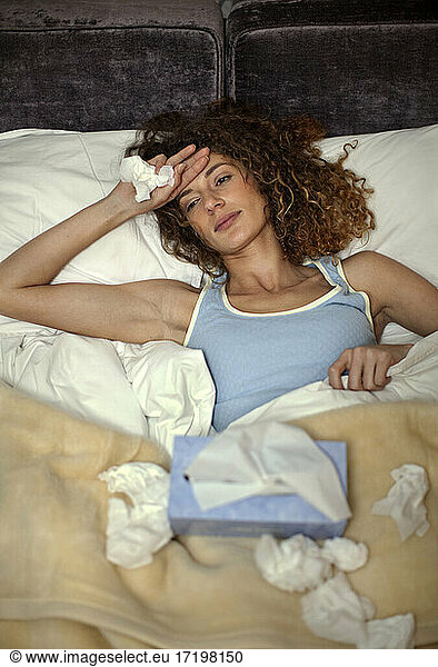 Sick woman resting while lying on bed at home