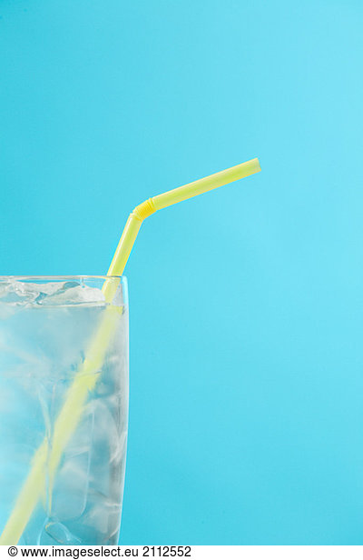 Side portion of clear glass of water with yellow drinking straw