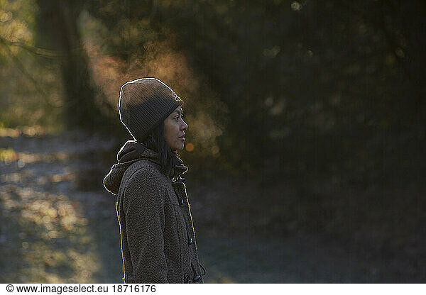 Side profile of Asian woman enjoying the cold weather blowing mist