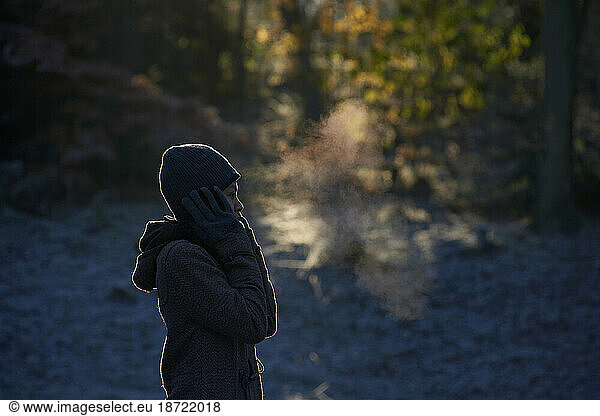 Side profile of Asian woman enjoying the cold weather blowing mist