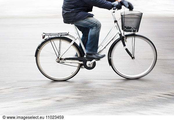 Side view low section of man riding bicycle on snow covered street