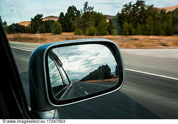 Side-view mirror reflection of car driving along State Highway 8