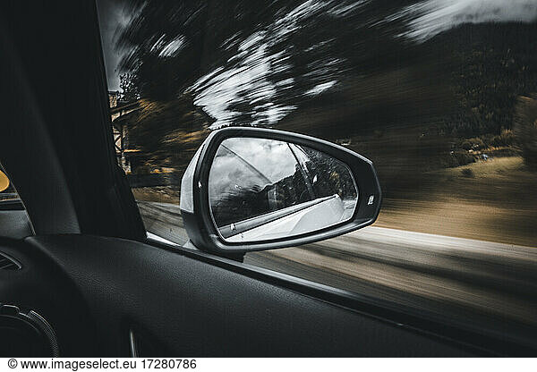 Side-view mirror reflection of moving car