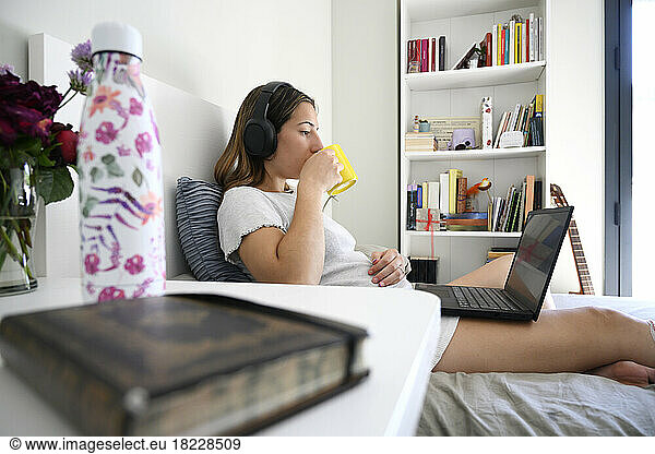 Side view of a beautiful woman playing on the laptop  lying on bed