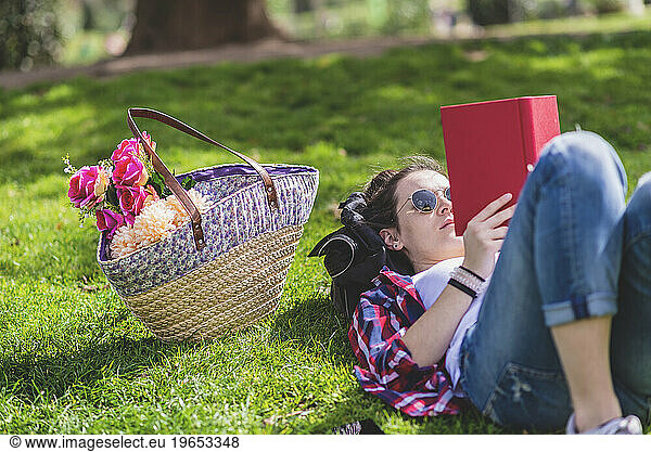 Side view of a hipster happy woman lying on grass in sunny day a
