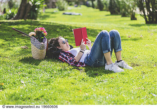 Side view of a hipster happy woman lying on grass in sunny day a