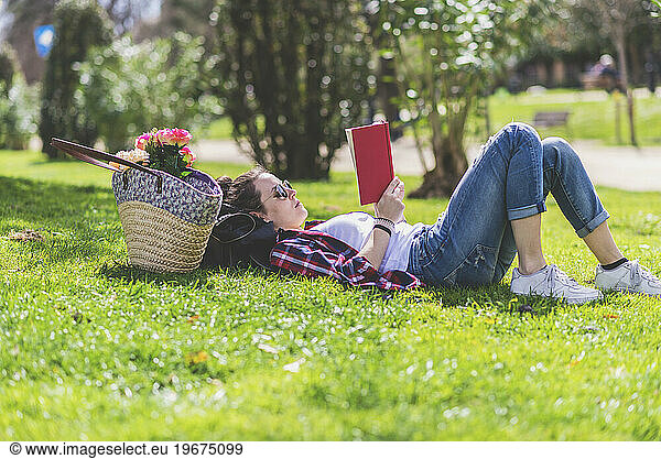 Side view of a hipster happy woman lying on grass in sunny day a