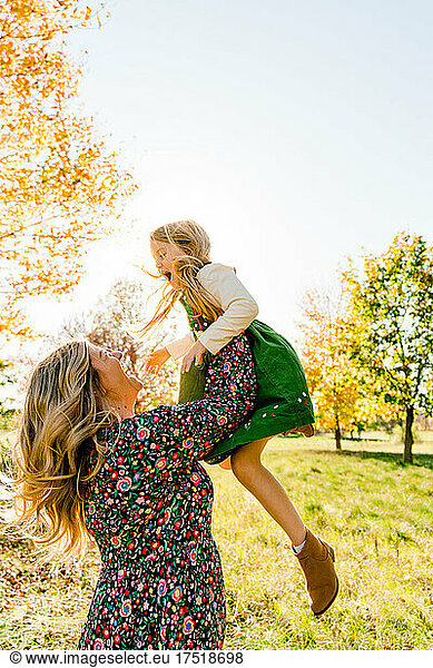 Side view of a mother throwing her daughter into the air