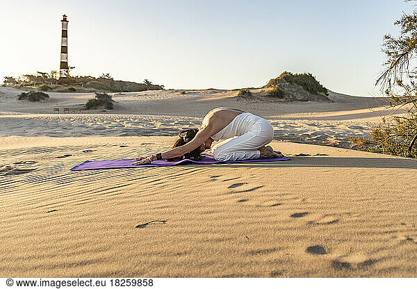 Side view of a woman training Head to Knee pose while doing yoga