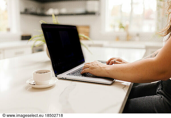 Side view of a woman working on computer with coffee inside