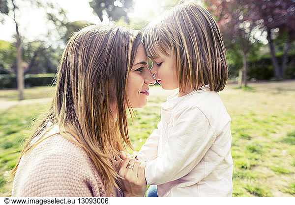 Side view of affectionate mother and daughter head to head in park
