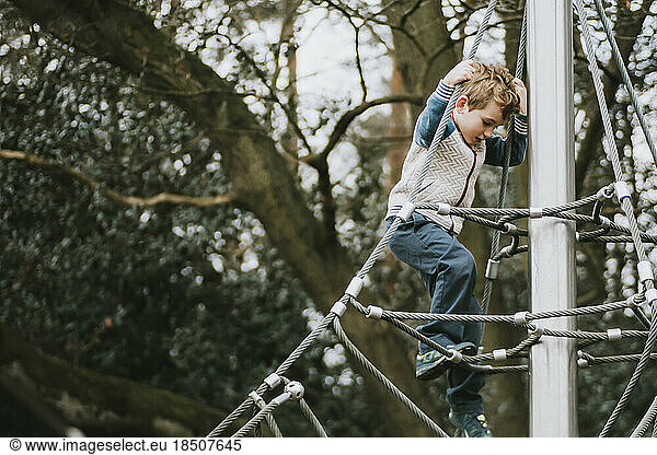 Side view of boy climbing down climbing frame