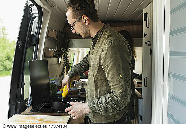 Side view of boyfriend preparing food with girlfriend in motor home