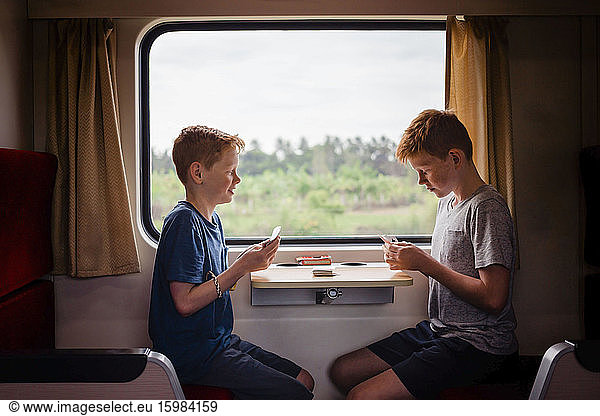 Side view of boys playing cards while traveling in train  Thailand  Asia