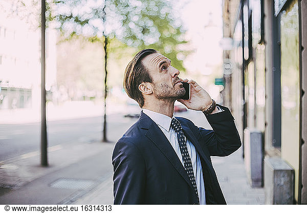 Side view of businessman talking on phone in city