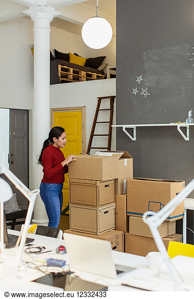 Side view of businesswoman examining cardboard box at creative office
