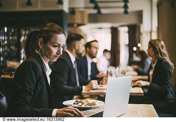 Side view of businesswoman using laptop in restaurant