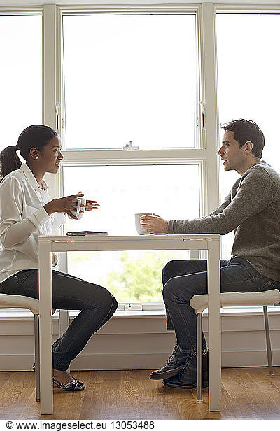 Side view of colleagues having coffee at table in office