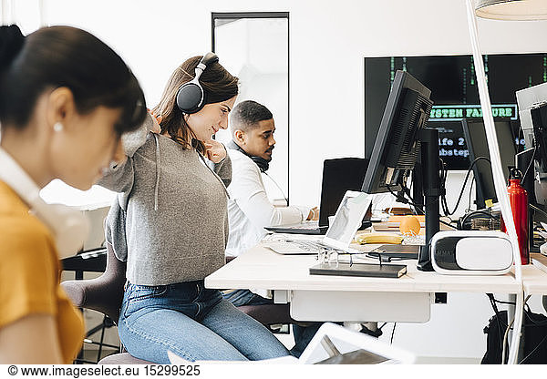 Side view of computer programmers working at desk while sitting in office