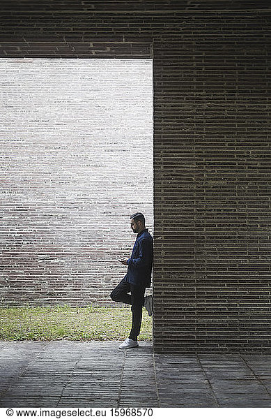 Side view of contemplating man standing by wall