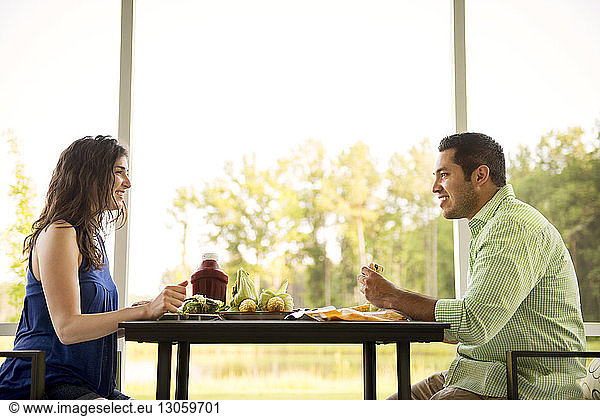 Side view of couple having discussion while eating food at table