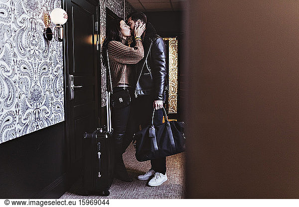 Side view of couple kissing at entrance of hotel room