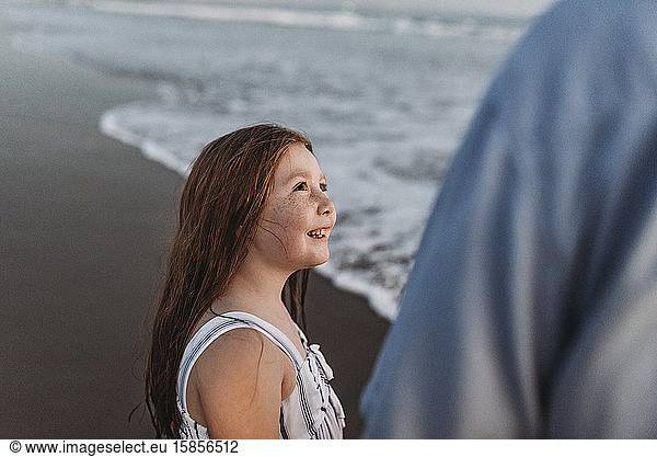 Side view of daughter looking at father and smiling at dusk in ocean