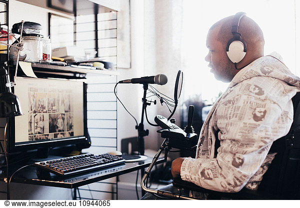 Side view of disabled man wearing headphones while looking at computer