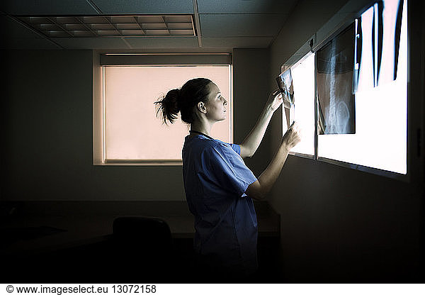 Side view of doctor examining x-rays on diagnostic medical tool in hospital