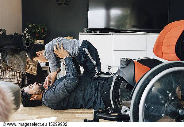 Side view of father playing autistic son while lying on floor at home