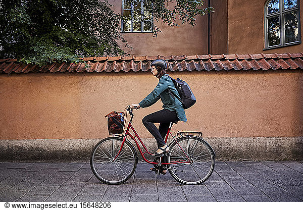 Side view of female engineer riding bicycle on street in city