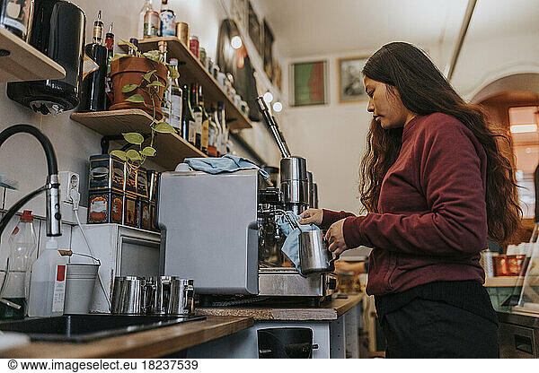 Side view of female entrepreneur making coffee in cafe