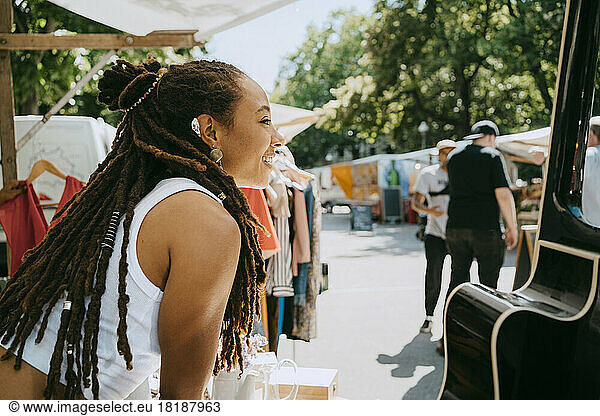 Side view of female owner with dreadlocks in stall at flea market