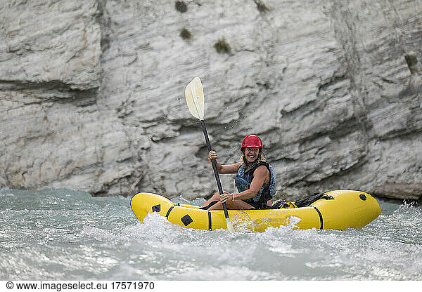 Side view of female paddler in a river canyon.