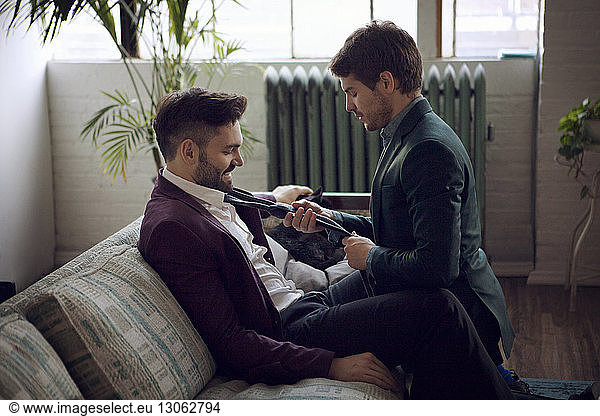 Side view of gay man tying boyfriend's necktie