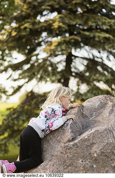 Side view of girl climbing rock at field
