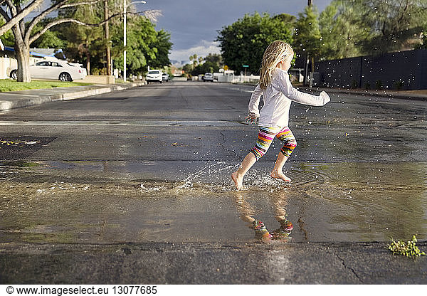 Side view of girl running on wet street during rainy season