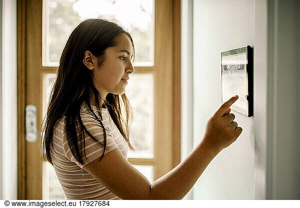Side view of girl using home automation through tablet PC mounted on wall