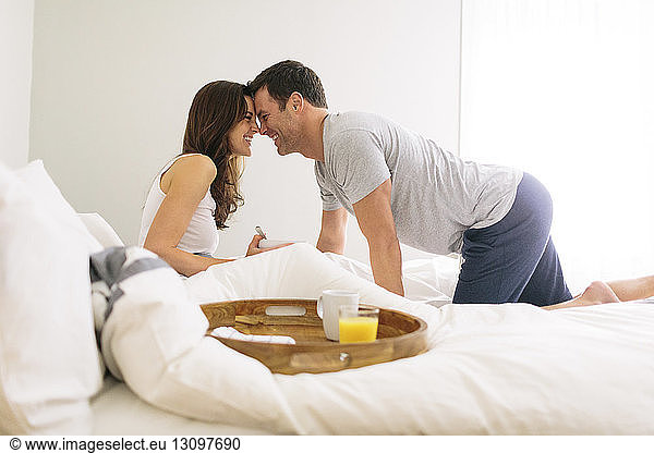 Side view of happy couple face to face in bed at home