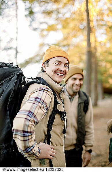 Side view of happy young man with backpack by male friend